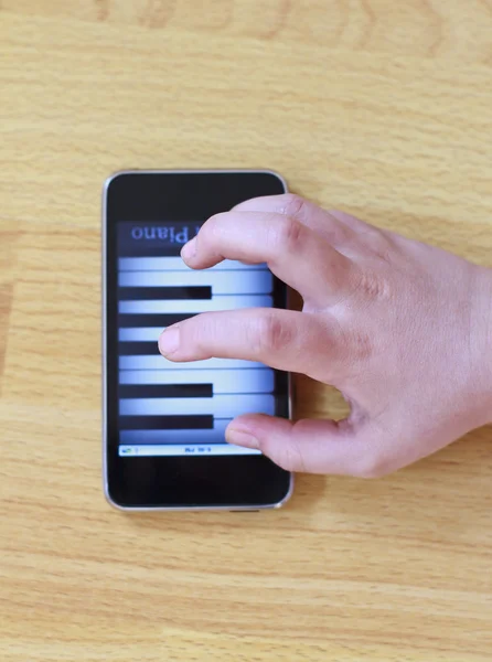 Игра на фортепиано на современном сенсорном экране телефона — стоковое фото