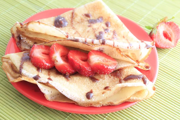 Pancakes with strawberries on red plate — Stock Photo, Image
