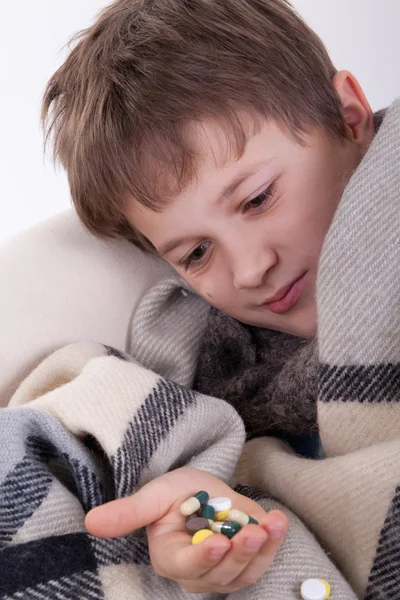 stock image The sick boy covered by a checkered plaid, holds in a hand of a tablet