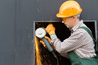 Worker in orange helmet with angle grinder. Half length portrait clipart