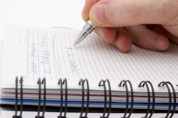 Hand med pennan skriver i anteckningsboken — Stockfoto
