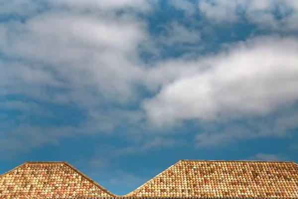 Bílé mraky modré obloze nad střechy oranžové deska — Stock fotografie
