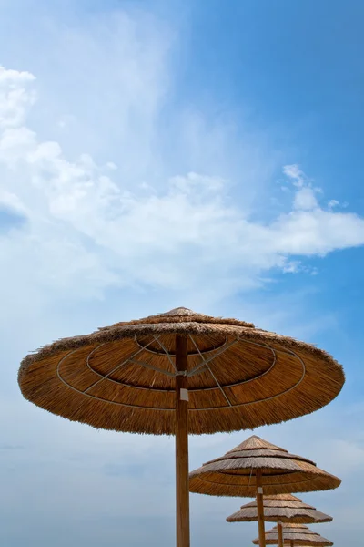 Соломенные зонтики и голубое небо — стоковое фото