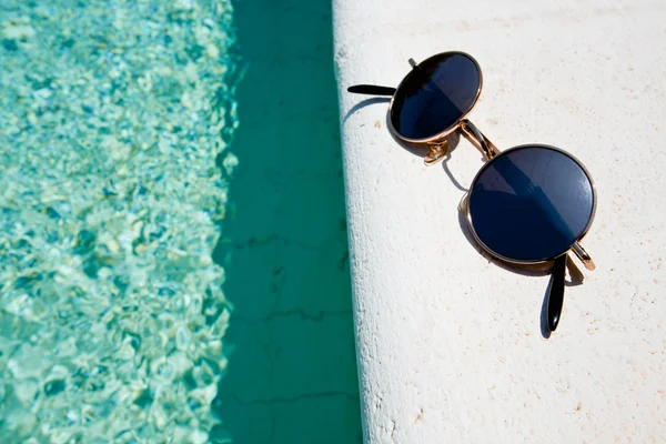 Black round sun glasses on pool board — Stock Photo, Image