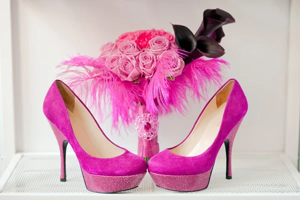Buquê nupcial de rosas e sapatos rosa estão em uma prateleira — Fotografia de Stock