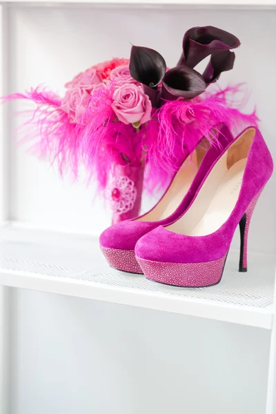 Brautstrauß aus Rosen und rosa Schuhen stehen in einem Regal lizenzfreie Stockfotos