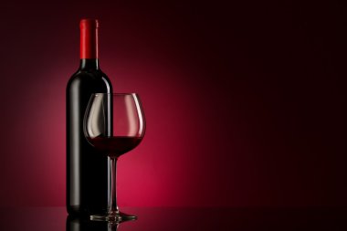 Bottle with red wine and glass on a red gradient