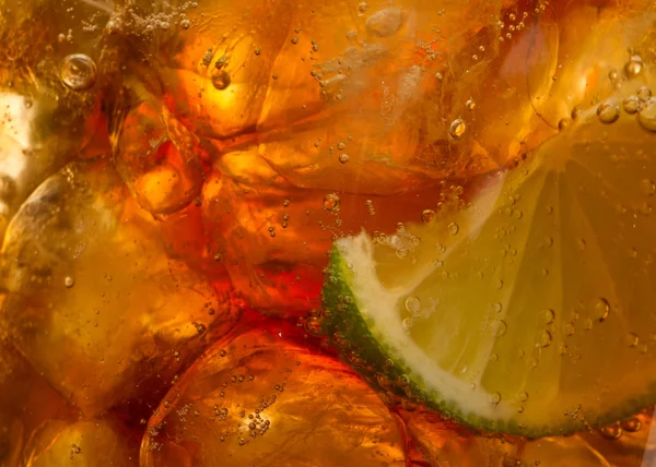 Close-up van verse bruine spatten vloeistof - cola met limoen en ijs — Stockfoto