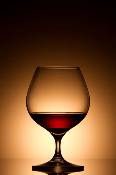 Glass of brandy over gold background — Stock Photo, Image