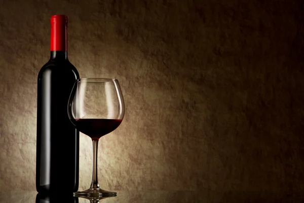 Fles met rode wijn en een glas op een oude steen — Stockfoto