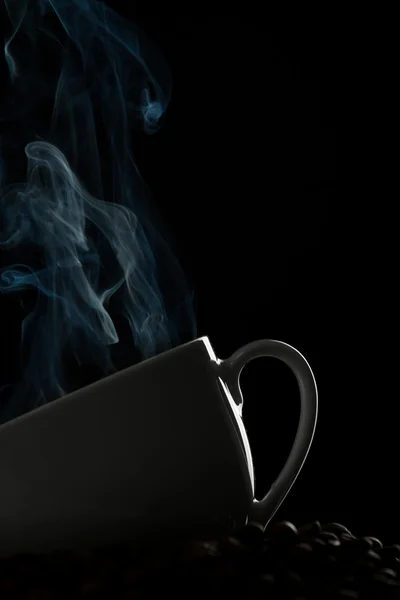 Taza de café caliente y grano en un negro —  Fotos de Stock