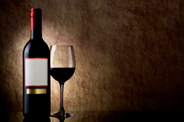 Fles met rode wijn en een glas op een oude steen — Stockfoto
