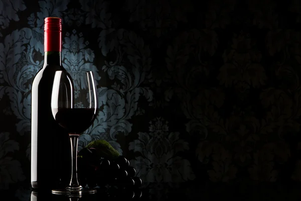 Бутылка с красным вином и стаканом на старом камне — стоковое фото