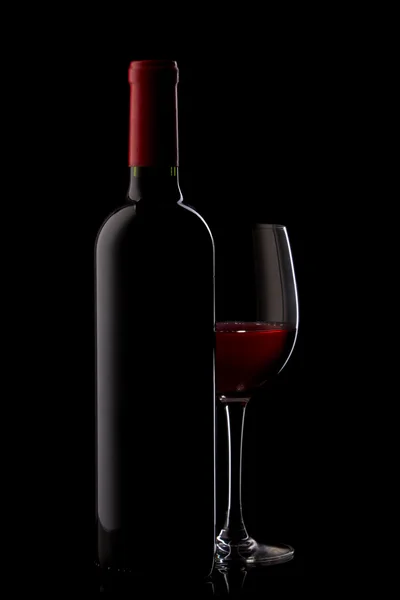 Fles met rode wijn en een glas op een rood kleurverloop — Stockfoto