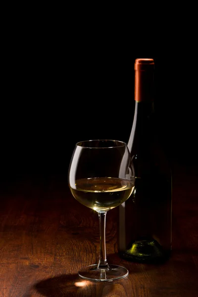 Bottle and a glass of wine on a wooden table — Stock Photo, Image