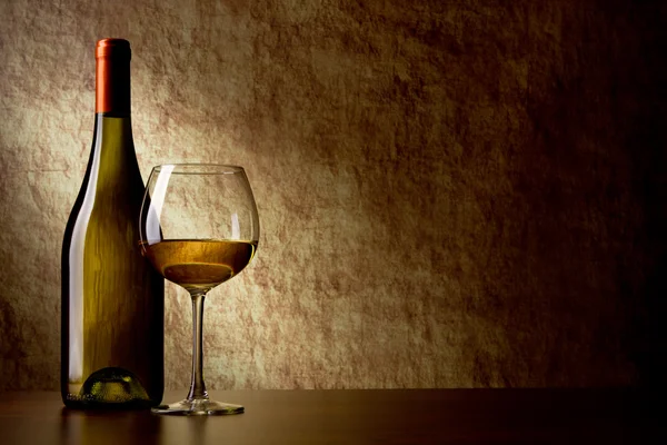 Garrafa com vinho branco e copo em uma pedra velha. vidro no fo — Fotografia de Stock
