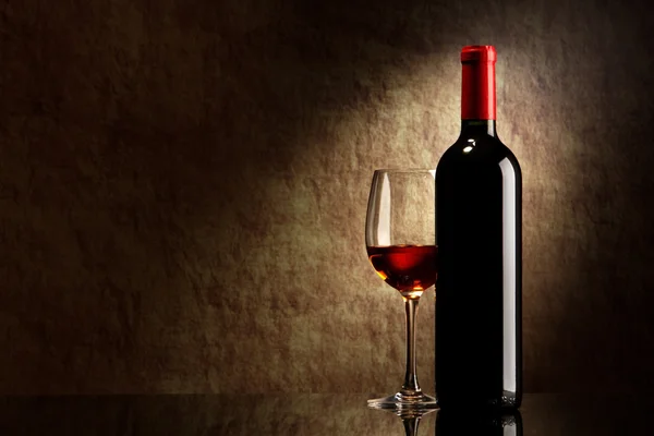 Flasche mit Rotwein und Glas auf einem alten Stein — Stockfoto