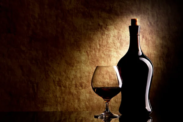 Cognac Bicchiere e bottiglia su un vecchio sfondo di pietra — Foto Stock
