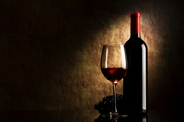 Flasche mit Rotwein und Glas und Trauben auf einem alten Stein Stockbild