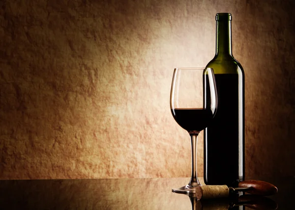 Groene fles met rode wijn en glas en kurk met een kurkentrekker op een oude sto — Stockfoto