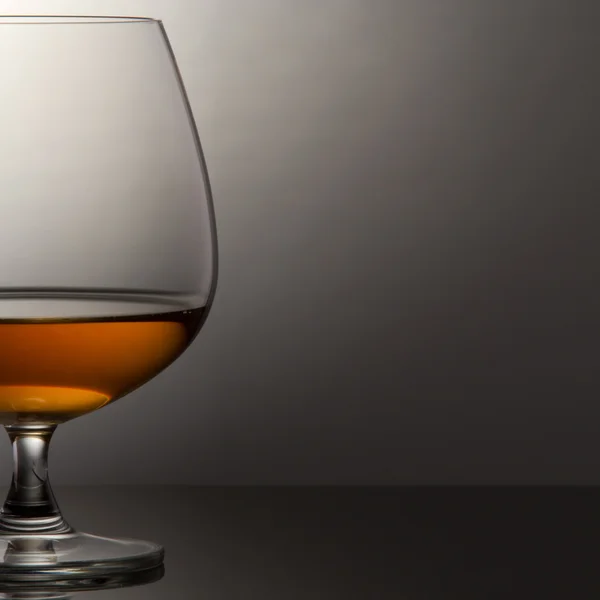 Glass of brandy over grey background — Stock Photo, Image