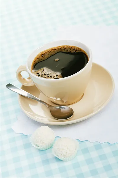 Czarna kawa z kokosa cukierki na niebieski Obrus — Zdjęcie stockowe