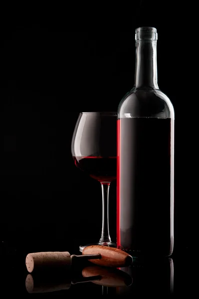Botella con vino tinto y copa y corcho con sacacorchos sobre un negro — Foto de Stock
