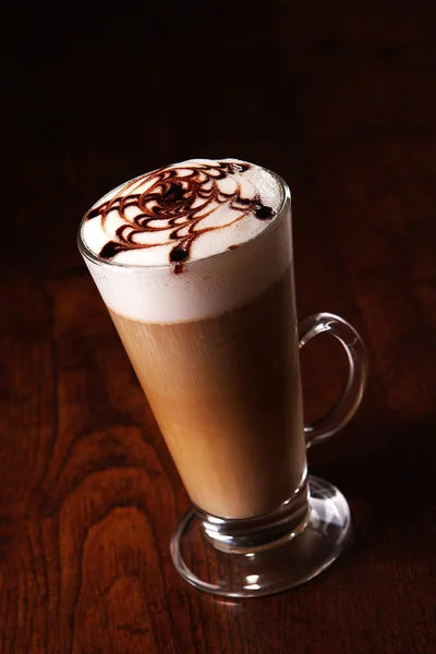 Hrnek latte na dřevěný stůl — Stock fotografie