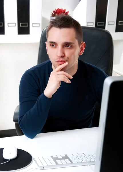 Молодий чоловік думає перед своїм комп'ютером — стокове фото