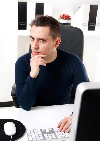 Jonge man denken achter zijn computer — Stockfoto