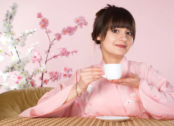 Beautiful girl sitting on a pink — Stock Photo, Image