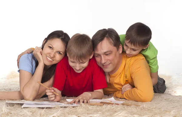 Leuke familie puttend uit een tapijt — Stockfoto