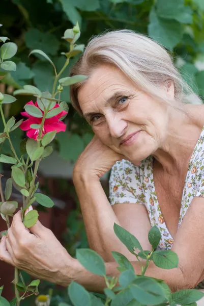 高齢女性の花を持つ — ストック写真