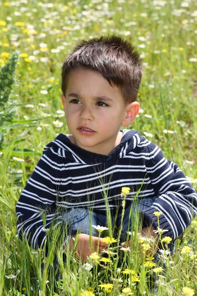 Мальчик присел на зеленое поле — стоковое фото