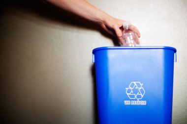 Arm dropping plastic bottling into recycling container clipart