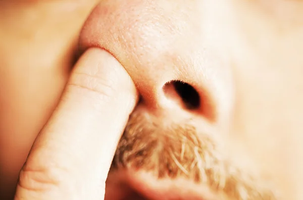 Man's vinger in de neus — Stockfoto