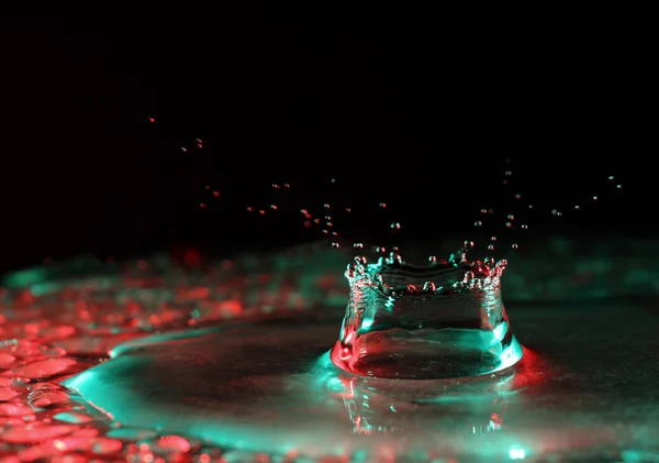 Plons in multi-gekleurde water op een zwarte achtergrond — Stockfoto