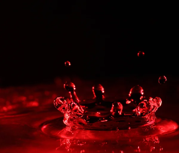 Water splash in red color with drops — Stock Photo, Image