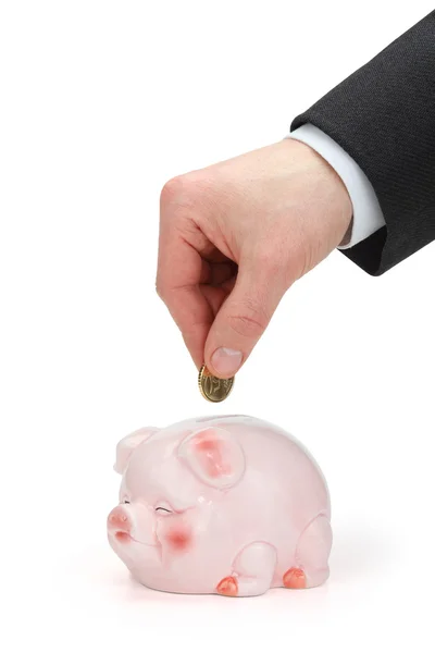 Hand des Geschäftsmannes hält eine Münze über Sparschwein. — Stockfoto