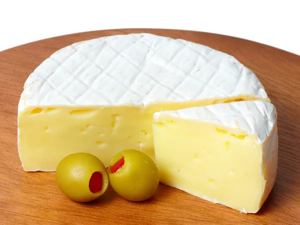 Wheel of cheese with green olives. — Stock Photo, Image