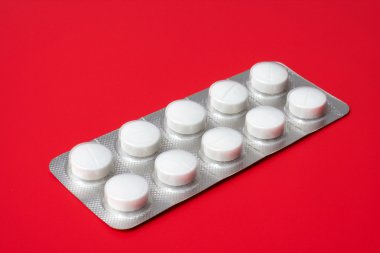 Blister pack containing tablets on a red background clipart