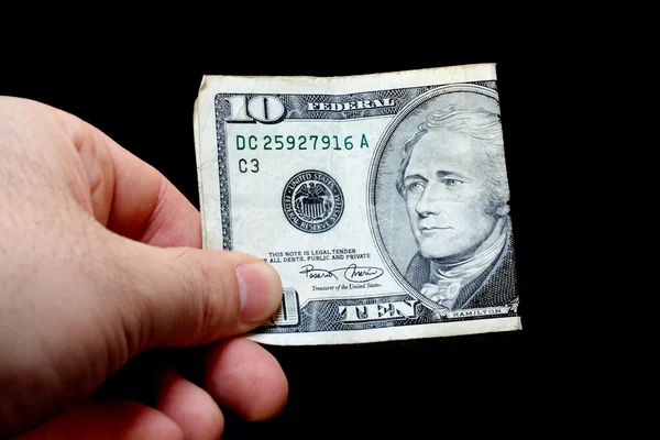 Чоловік тримає десять доларів, ізольований на чорному тлі — стокове фото