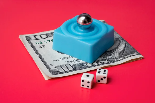 Dobbelstenen en marmeren staal over blauwe platform en tien dollar bill, op een rode bac — Stockfoto