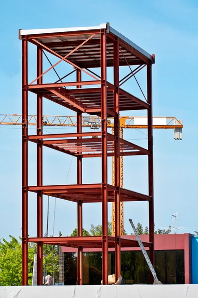 Стальная конструкция и строительный кран на фоне голубого неба — стоковое фото