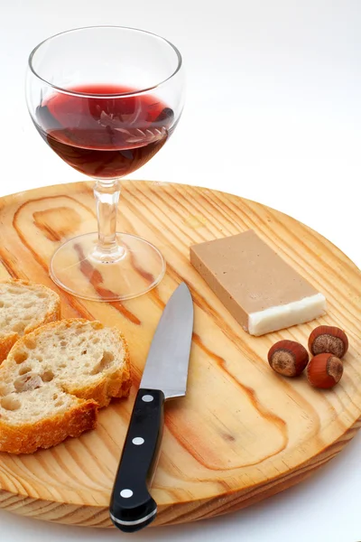 Pate, bread, glass of red wine, hazelnuts and knife on wood plat — Stock Photo, Image
