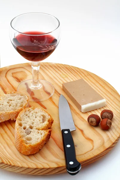 Pate, bröd, glas rödvin, hasselnötter och kniv på trä plat — Stockfoto