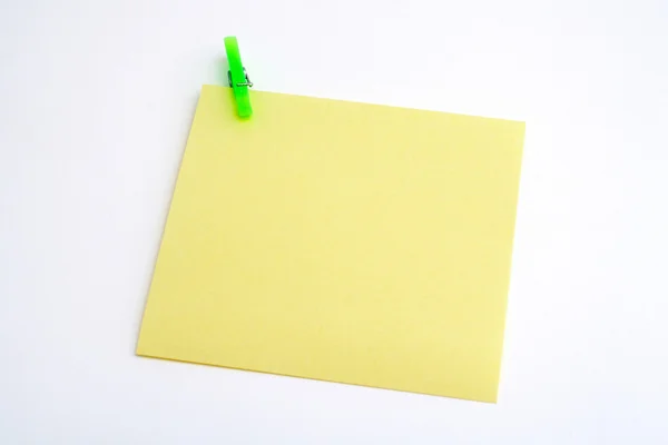 Papel amarillo aislado con abrazadera verde — Foto de Stock