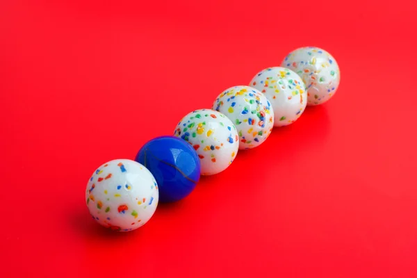 One blue ball amongst five white balls, Focus on blue ball with shallow DOF — Stock Photo, Image