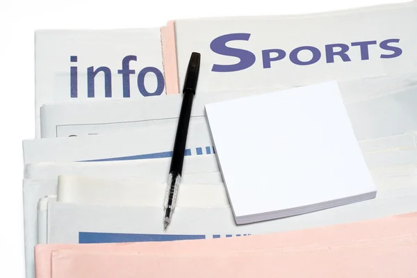 Note and pen, over stacked sports newspapers — Stock Photo, Image
