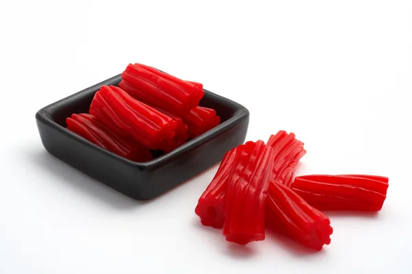 Kousky červené lékořice na černém mísa — Stock fotografie